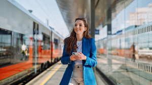 woman at rail station on phone smiling cheerfully