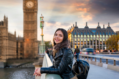 tourist woman in leather jacket standing on bridge in London big ben in background